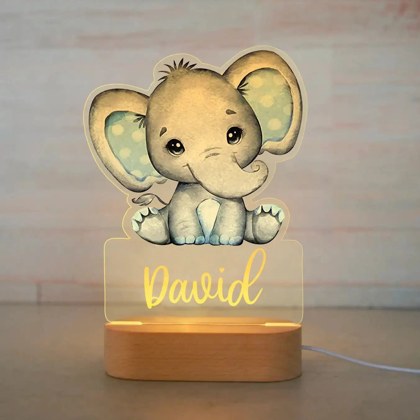 Gray elephant baby night light with blue ears and personalized name David on wooden base.
